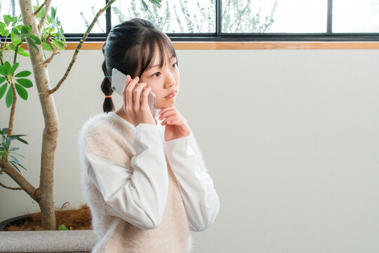 Elementary and middle school girls sitting on their sofas at home, talking on their smartphones.
