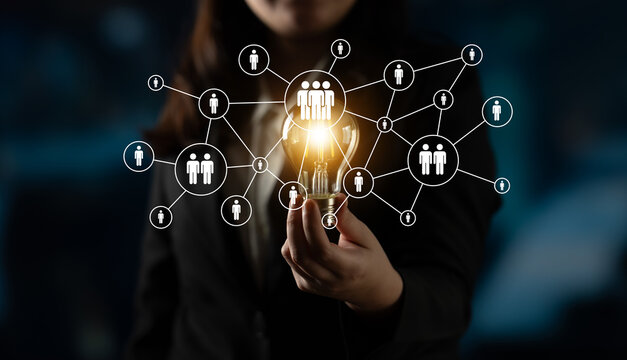A businesswoman holds a light bulb symbolizing innovative ideas within a network of connections, showcasing collaboration and modern technology in a professional environment. Ledger