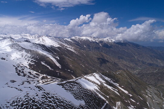 Aerial view of the snow-capped peaks and winding roads of Babusar Top in the rugged mountain landscape of Naran, Khyber Pakhtunkhwa, Pakistan.