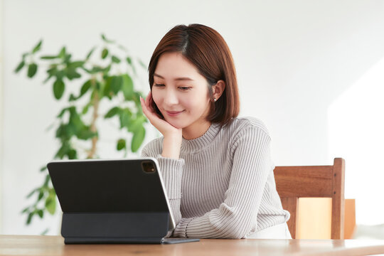 リビングでタブレットPCを見る女性
