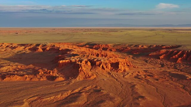 Aerial view of the Flaming Cliffs, featuring red sandstone formations and vast desert plains under a clear sky in Bulgan, Omnogovi, Mongolia.