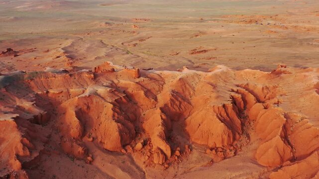 Aerial view of the Flaming Cliffs in the Gobi Desert, featuring dramatic red sandstone formations and rugged desert terrain in Bulgan, Omnogovi, Mongolia.
