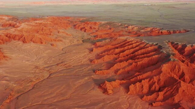 Aerial view of the Flaming Cliffs featuring dramatic red sandstone formations and rugged desert terrain in Bulgan, Omnogovi, Mongolia.