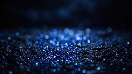Blue sparkling glitter on black surface with cinematic bokeh background and shallow depth of field