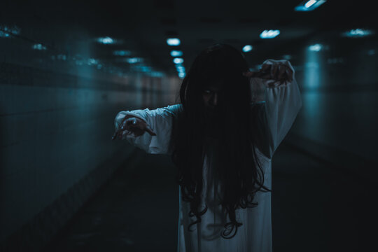 Halloween scary woman in white dress walking forward in dark corridor with eerie atmosphere, representing ghostly horror concept for seasonal thriller project or creepy autumn event background
