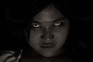 Fototapeta premium Halloween event featuring scary woman staring intently with glowing eyes in dark spooky night context creating creepy atmosphere for traditional horror celebration and spooky party promotion