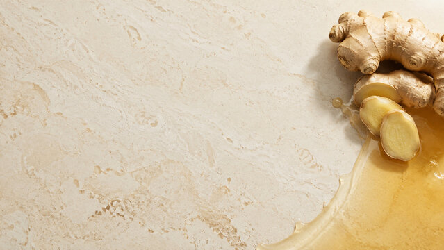 Fresh Ginger Root and Translucent Amber Wellness Liquid on Warm Stone with Natural Copy Space