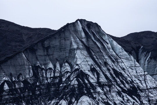 View of a glacier with striking black volcanic ash streaks contrasting against white ice in Iceland.