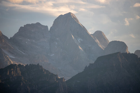 View of the Dolomites mountain range with jagged rocky peaks and soft golden hour light in Veneto, Italy.