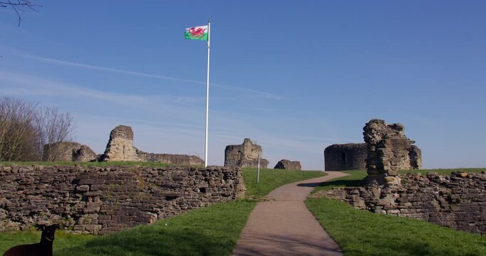 Extra wide shot of the entrance to Flint castle with the Welsh flag flying on a white flagpole