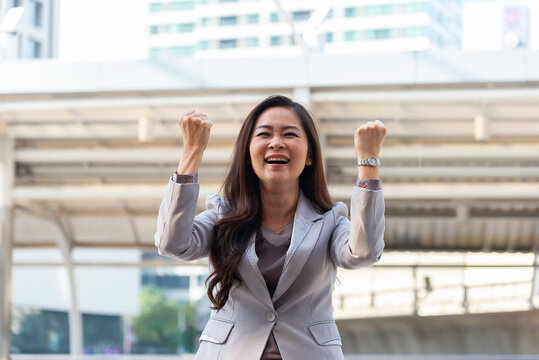Business woman in suit look to future on building background in city outdoor and celebrating for success work at the office, investment concept, success concept