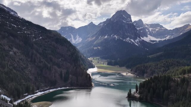 Obersee Switzerland aerial view alpine lake surrounded by snowy mountains, forested valley and dramatic peaks, Glarus Swiss alps winter spring landscape.