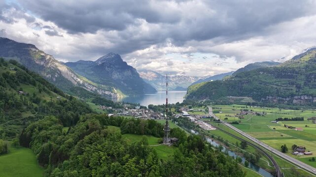 Aerial view across the Weesen and Walensee region toward the Biberlichopf, where a prominent Swisscom transmitter rises above the wooded hill near Ziegelbr&uuml;cke and the surrounding Alpine landscape.