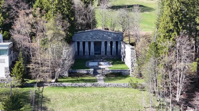 Paxmal Switzerland aerial drone push view to beautiful stone temple monument garden forest landscape alps.