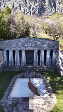 Paxmal Switzerland vertical aerial drone view of stone temple monument mountain forest alps landscape, drone pushes towards.