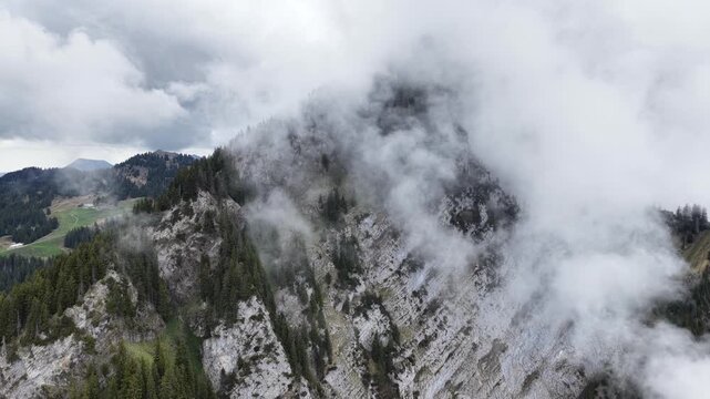 Amden Switzerland aerial drone flying through stunning thick clouds mountain ridge forest alpine landscape.