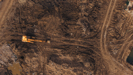 Yellow excavator moving earth across cleared construction ground industrial land development site © VisualTreat12