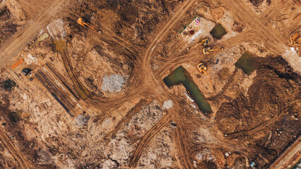 Excavator clearing land at construction site with dirt roads and water pond industrial development © VisualTreat12