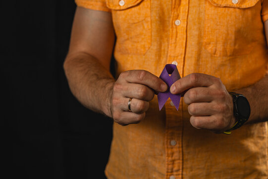 Man holds a purple awareness ribbon for health campaign in studio setup