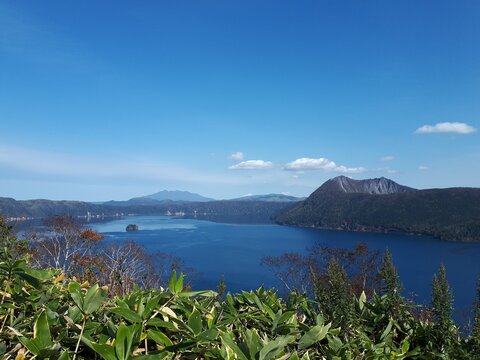 Lake Mashu and surrounding mountains under blue sky in Hokkaido, Japan