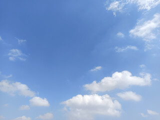 Fototapeta premium Beautiful blue sky with fluffy white cumulus clouds and delicate wispy clouds, creating a peaceful natural background with ample copy space.