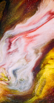 Glitter paint. Fluid art. Defocused yellow pink purple color shiny pigment blend sparkling texture spilling on abstract background.