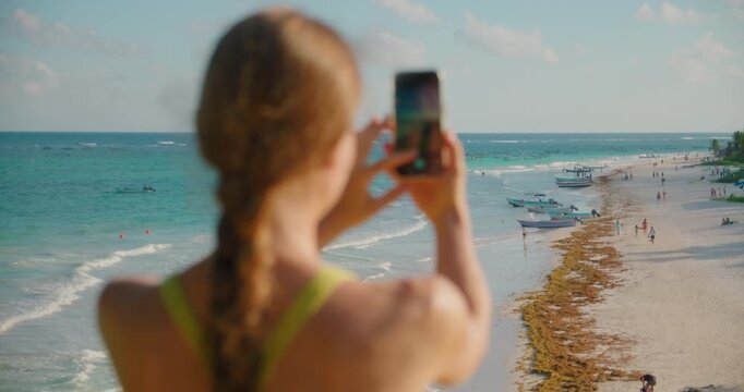 Woman takes photo of tropical beach Santa Fe with smartphone in Tulum Mexico. Parque National Tulum.