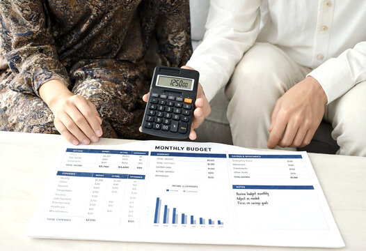 Couple reviewing monthly budget with calculator and financial documents for expense tracking and planning