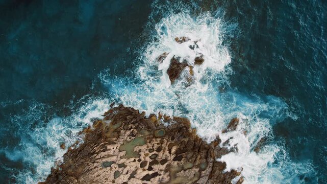 Crashing sea waves splash over jagged shoreline at rocky coast