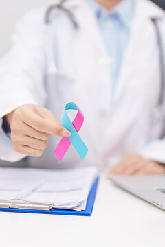 Doctor giving blue and pink ribbon to patient for concept of October male Breast Cancer Awareness month, National Cancer Survivors Month and Pink October Healthcare and February world cancer