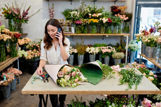 Florist Talking on Phone While Preparing a Bouquet in Flower Shop