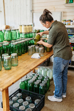 Small Business Owner Organizing Reusable Glass Jars in Refill Shop