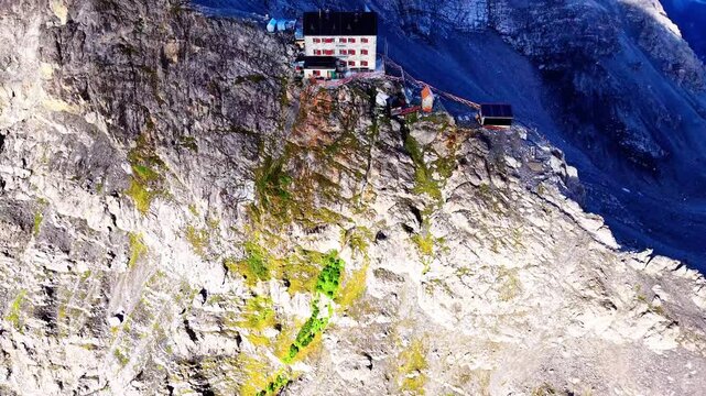 Aerial view of Payer Hutte on the rugged rocky slopes of Ortler Mountain with steep cliffs and patches of moss in Sulden, Trentino-Alto Adige, Italy.