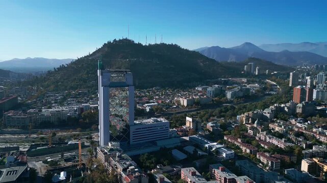 Aerial view of the Gran Torre Santiago skyscraper rising above the urban landscape of Santiago with San Cristobal Hill in the background in Santiago, Santiago Metropolitan, Chile.