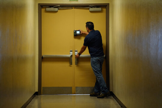 Fire Door Inspector Testing Closing Cycle in Institutional Corridor
