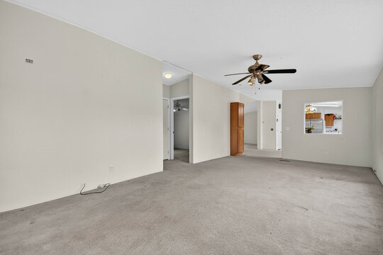 Unoccupied Room With Airy Openness, Spacious Vacant Area Featuring Ceiling Fan And Soft Carpeting