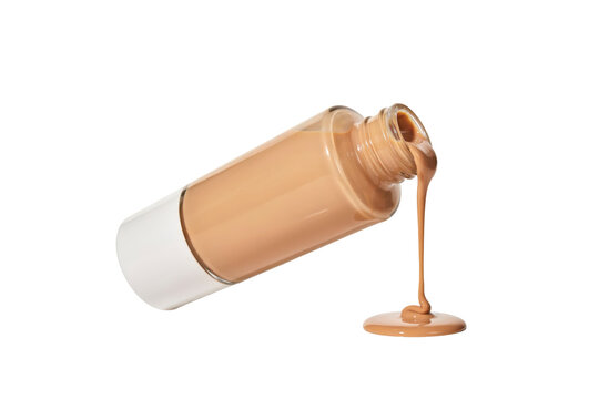Liquid beige foundation makeup pouring out of a clear glass bottle with white cap isolated on a transparent background