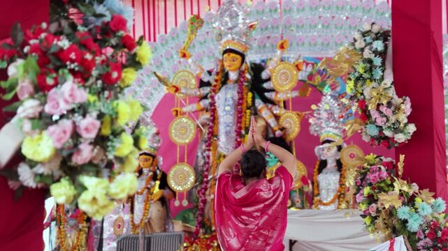 women Devotee Offering Prayers Before a blurred Decorated Goddess Durga Idol During Durga Puja