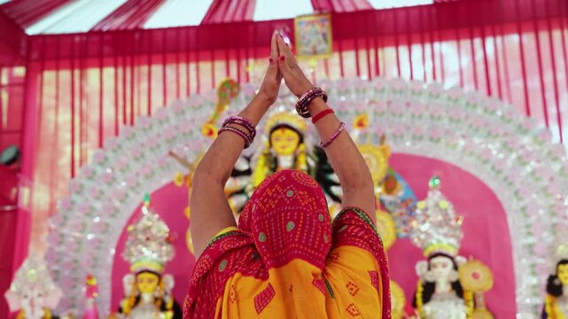 hindu worshipper praying with folded hands before durga idol at durga puja celebration