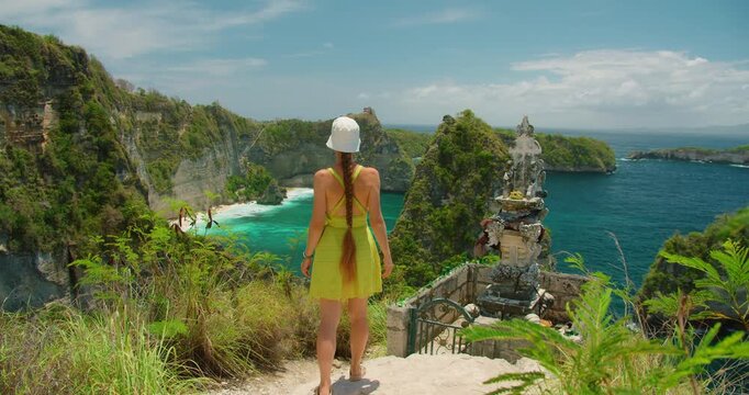 Woman with long braid at Hindu temple shrine overlooking Diamond Beach coast in Nusa Penida Bali