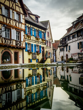 Eguisheim timber framed houses reflecting in puddle water