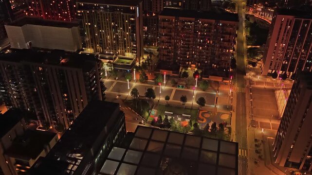 Wembley Park glows at night with high rise residential buildings, illuminated streets and pedestrian spaces in Brent, London, England, United Kingdom, captured in a drone forward flyover.