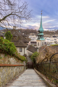 Stone stairway descending toward a historic church tower and traditional buildings in Salzburg Old Town, Austria.