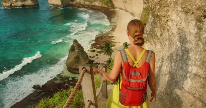 Woman explores cliffside path overlooking Diamond Beach and rocky coast in Nusa Penida Bali