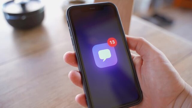 Hand holding smartphone displaying number of unread messages on screen