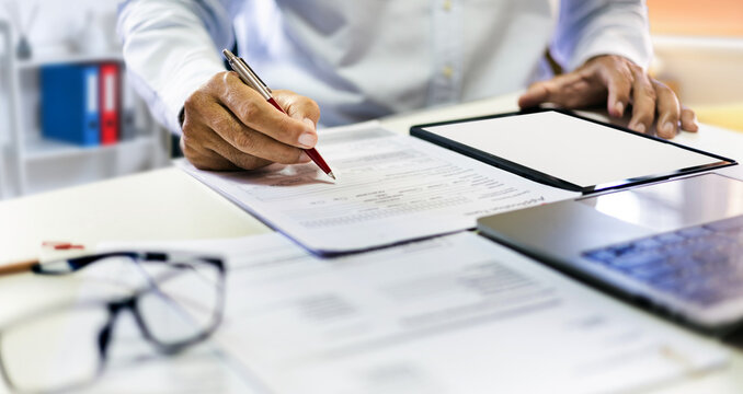 close up shot, asian man holding pen work on desk with business documents and doing online business, E-commerce via digital tablet and laptop