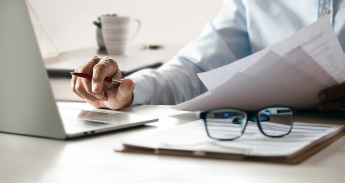 close up shot, hand of businessman holding pen working with laptop reading and learning online business from documents to start online business, E-commerce at home via computer laptop