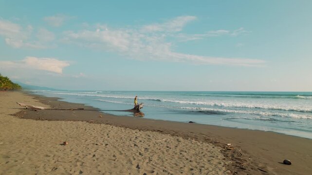 Lonely traveler walking near driftwood on deserted Linda beach in Costa Rica