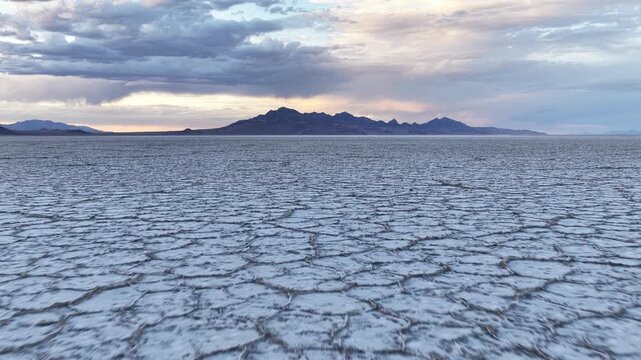 Aerial view of the vast salt crust and cracked earth patterns of the Bonneville Salt Flats at sunset in Tooele County, Utah, United States.