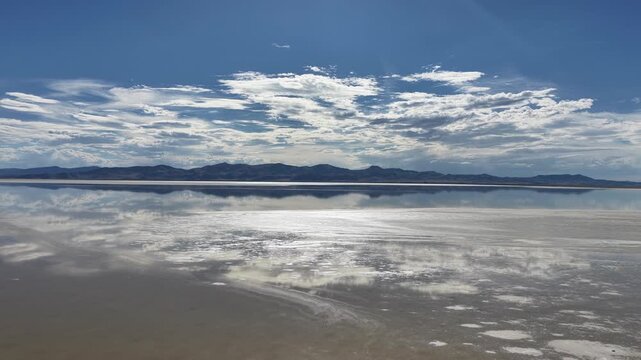 Aerial view of the Great Salt Lake reflecting the dramatic clouds and blue sky over the vast saline landscape in Salt Lake City, Utah, United States.